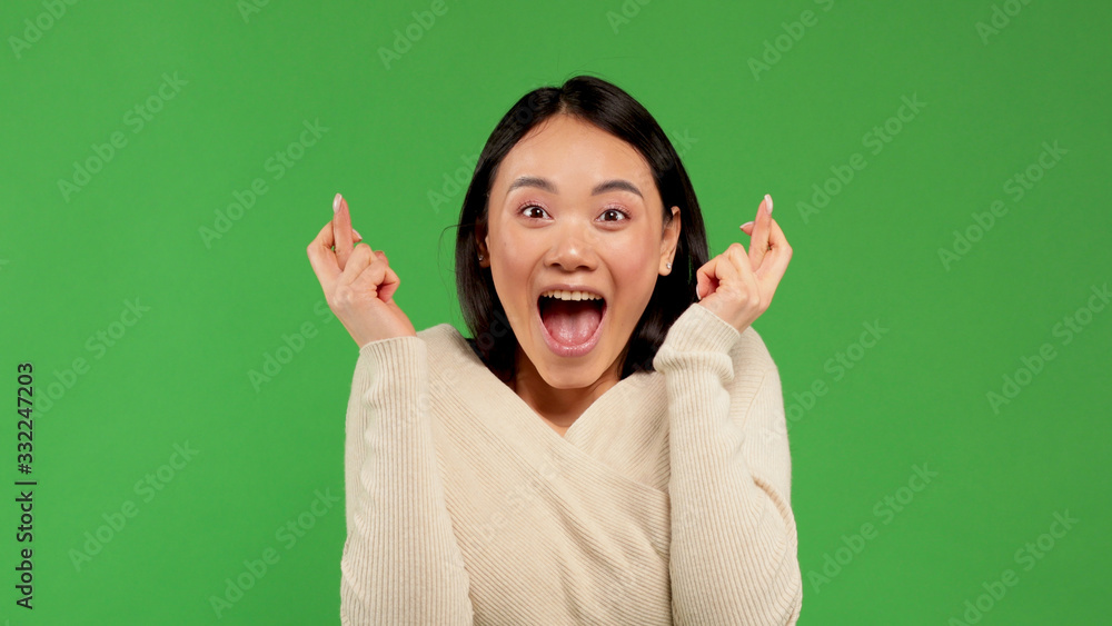 A satisfied emotional European woman clenches her fists, celebrates the celebration, stands on a green background, escapes from good feelings A satisfied emotional European woman clenches her fists, celebrates the celebration, stands on a green background, escapes from good feelings