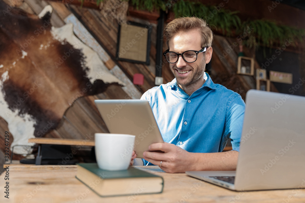 businessman sitting at desk working on his tablet happy businessman sitting at desk working on his tablet happy
