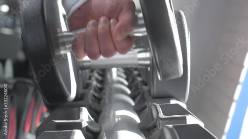 A man's hand takes a dumbbell in the gym. Close up. Muscular arm in the gym. Training, sports, hand, dumbbell. The concept of a healthy lifestyle. photo