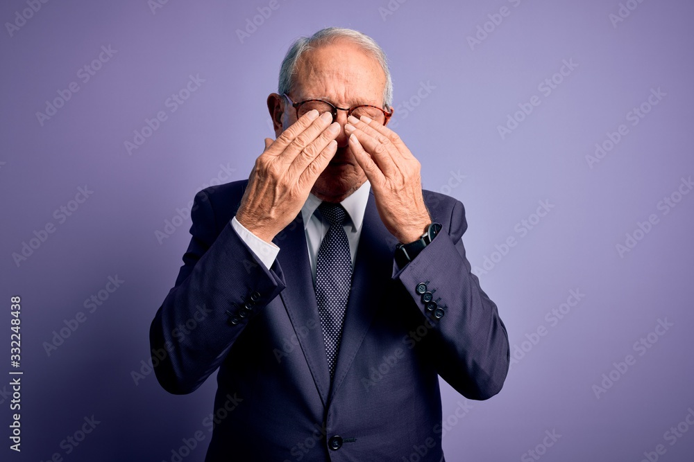 Grey haired senior business man wearing glasses and elegant suit and tie over purple background rubbing eyes for fatigue and headache, sleepy and tired expression. Vision problem