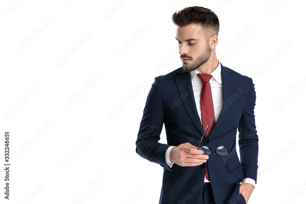 businessman standing and holding glasses while looking down with attitude businessman standing and holding glasses while looking down with attitude