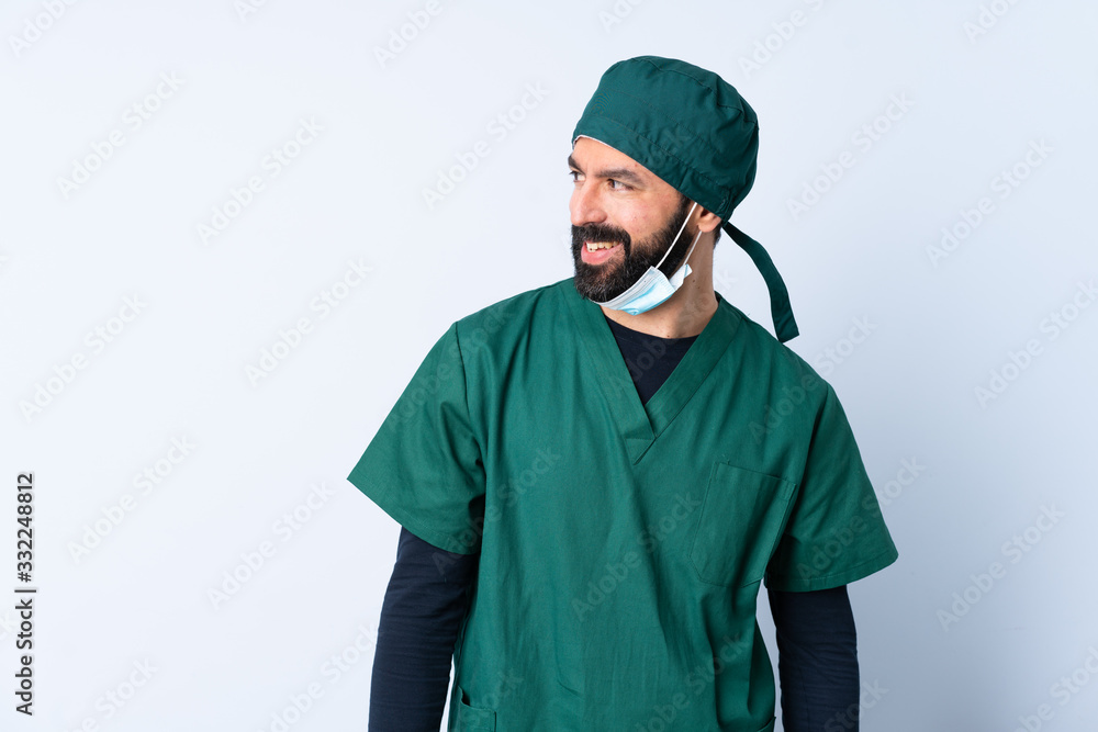 Surgeon man in green uniform over isolated background looking to the side and smiling Surgeon man in green uniform over isolated background looking to the side and smiling