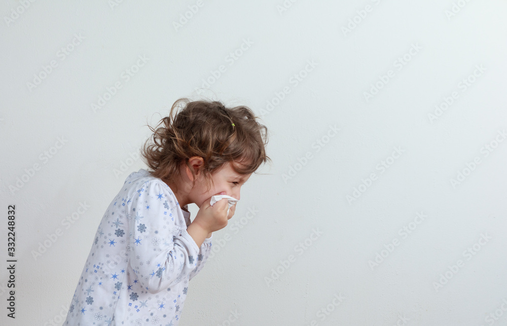 Young girl sneezing into a paper handkerchief, facing away, in front of a white background. Young girl sneezing into a paper handkerchief, facing away, in front of a white background.