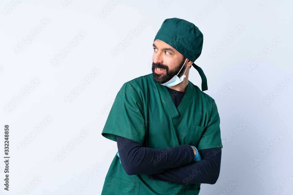 Surgeon man in green uniform over isolated background looking to the side and smiling