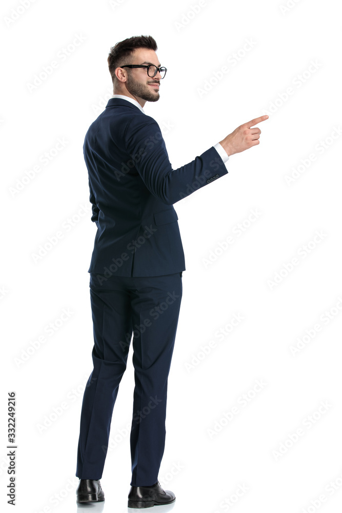 businessman standing with hand in pocket and pointing aside happy businessman standing with hand in pocket and pointing aside happy