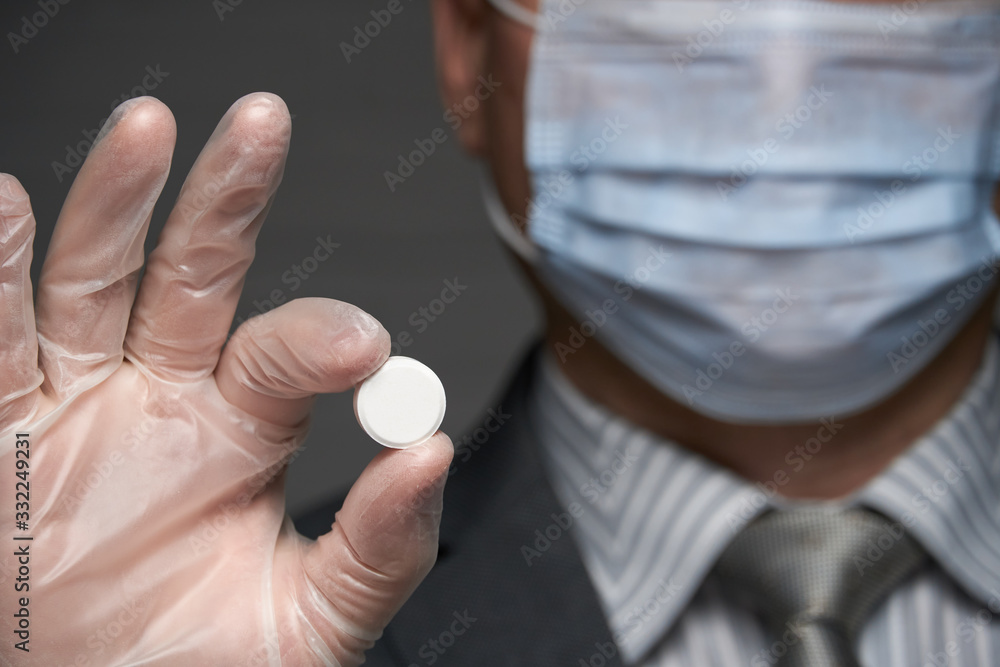 a man with a mask on his face for antivirus individual protection showing a pill - healthcare and medicine concept, prevention tips