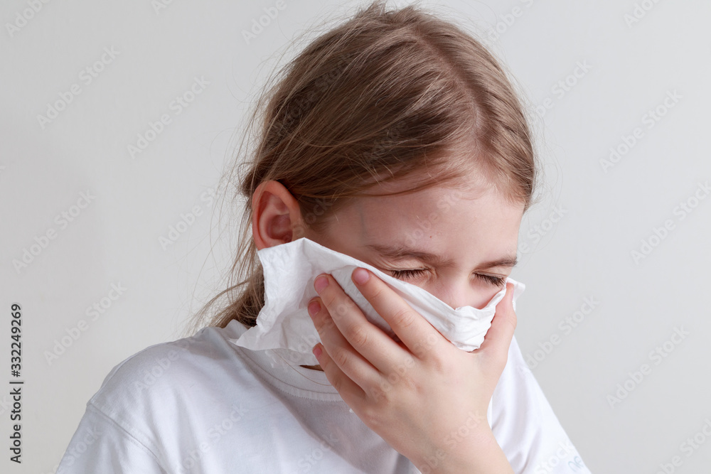 Young girl coughing into a paper handkerchief in front of a white background Young girl coughing into a paper handkerchief in front of a white background