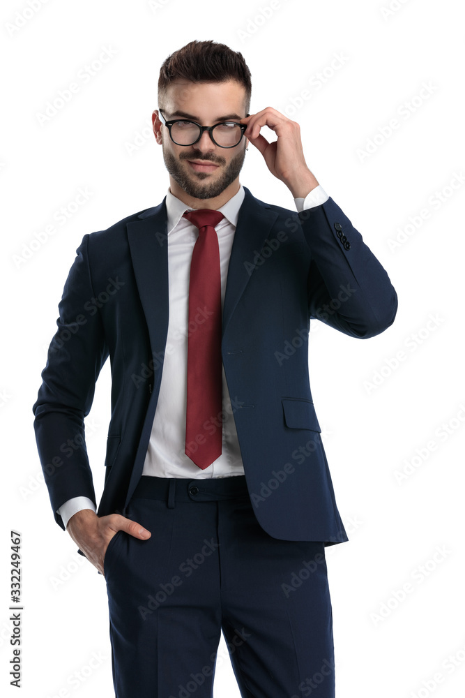 formal man standing with hand in pocket and fixing glasses formal man standing with hand in pocket and fixing glasses