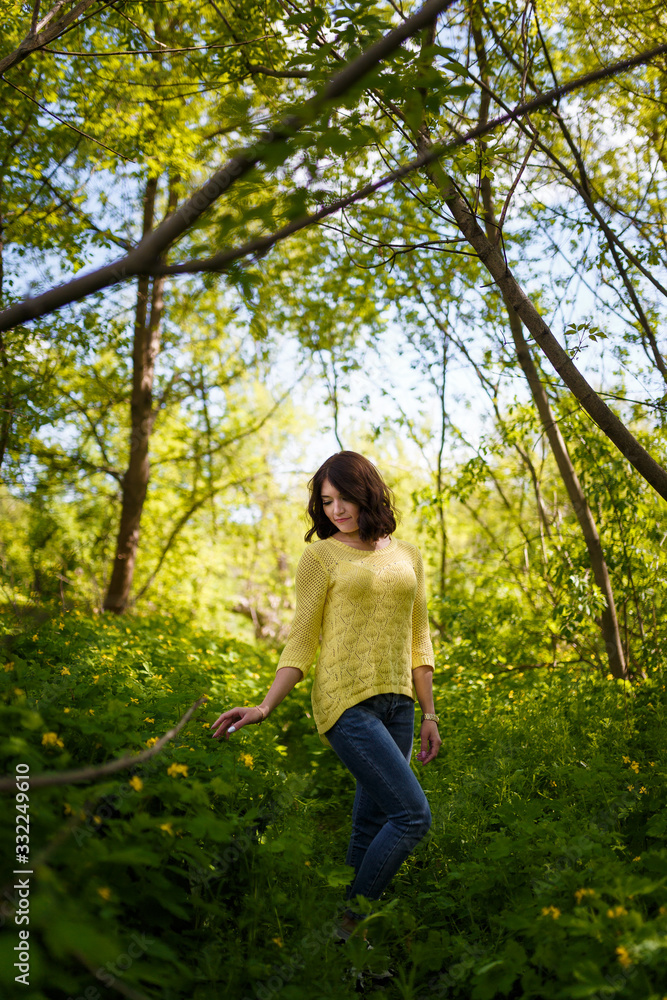 Beautiful young woman with short hair in yellow sweater among blossoming spring celandine flowers. Beautiful young woman with short hair in yellow sweater among blossoming spring celandine flowers.