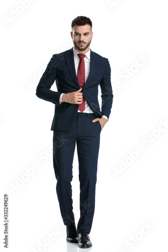 formal guy walking with hand in pocket fixing jacket serious