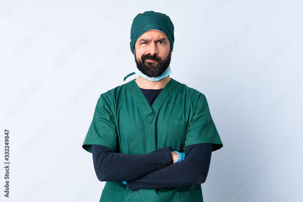 Surgeon man in green uniform over isolated background with unhappy expression Surgeon man in green uniform over isolated background with unhappy expression