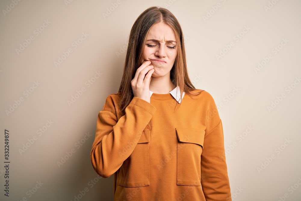 Young beautiful redhead woman wearing casual sweater over isolated white background touching mouth with hand with painful expression because of toothache or dental illness on teeth. Dentist Young beautiful redhead woman wearing casual sweater over isolated white background touching mouth with hand with painful expression because of toothache or dental illness on teeth. Dentist