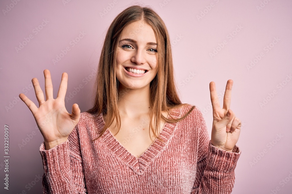 Young beautiful redhead woman wearing casual sweater over isolated pink background showing and pointing up with fingers number seven while smiling confident and happy. Young beautiful redhead woman wearing casual sweater over isolated pink background showing and pointing up with fingers number seven while smiling confident and happy.