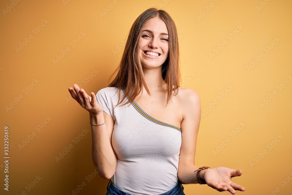 Young beautiful redhead woman wearing casual t-shirt over isolated yellow background smiling cheerful with open arms as friendly welcome, positive and confident greetings Young beautiful redhead woman wearing casual t-shirt over isolated yellow background smiling cheerful with open arms as friendly welcome, positive and confident greetings