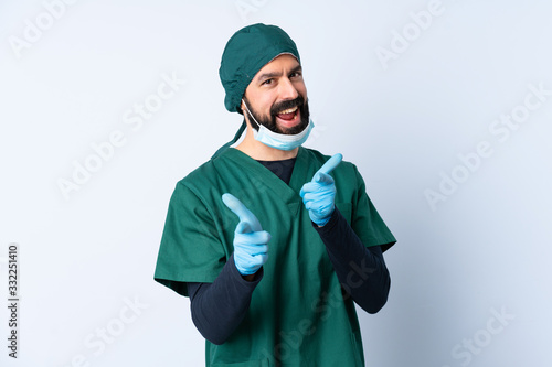 Surgeon man in green uniform over isolated background pointing to the front and smiling