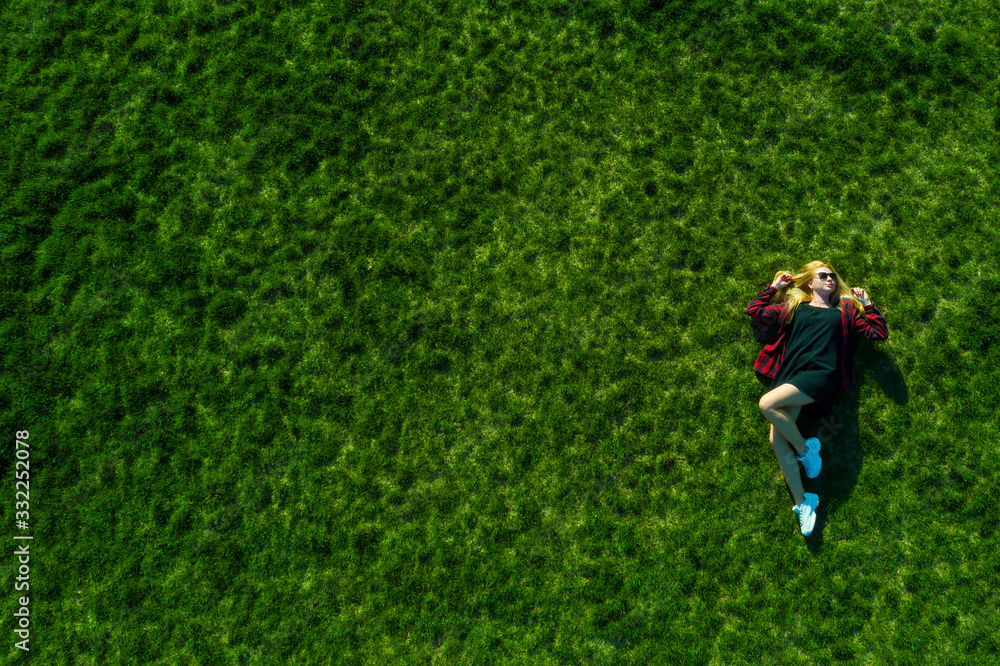 Happy woman relaxing on the grass. Aerial top view of vacation during sunny summer day Happy woman relaxing on the grass. Aerial top view of vacation during sunny summer day