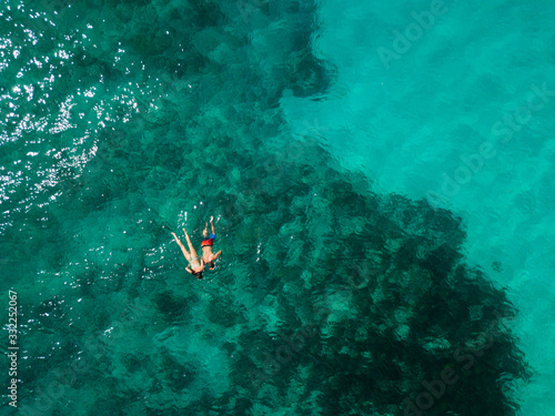 Snorkeling couple in the middle of the Indian Ocean, coral reefs, green water, from high above. Birds eye view. 