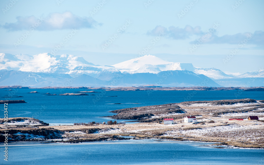 Small islands off the coast of Iceland with snowcapped mountains in the background