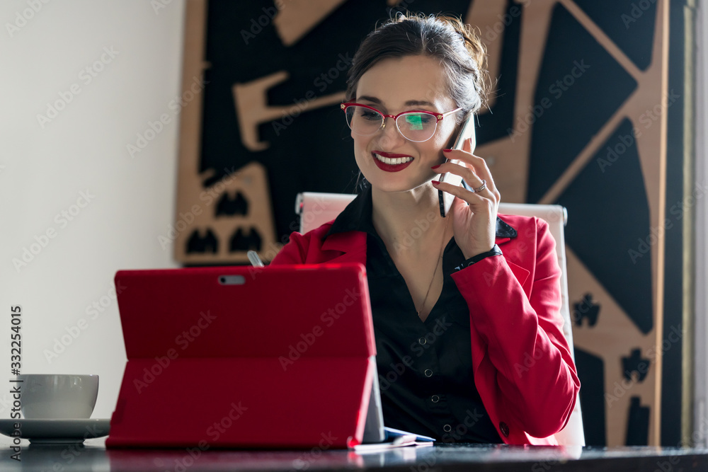 Businesswoman working with her computer while being on the phone Businesswoman working with her computer while being on the phone