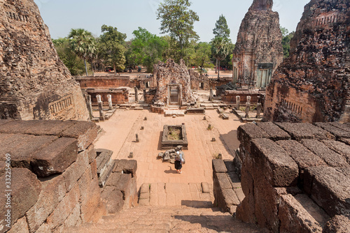 Lonely tourist exploring sculptures and stone towers of 10th century Wat Pre Rup temple  Cambodia. Historical landscape and tall pyramid structure in Angkor