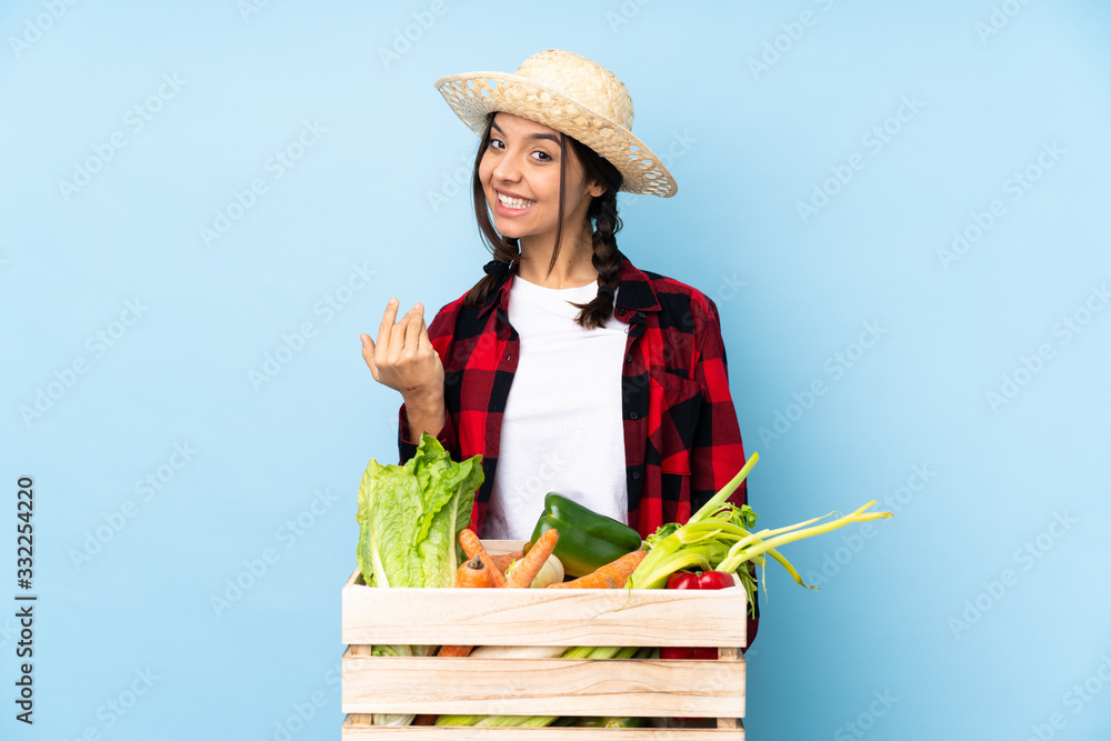 Young farmer Woman holding fresh vegetables in a wooden basket inviting to come with hand. Happy that you came