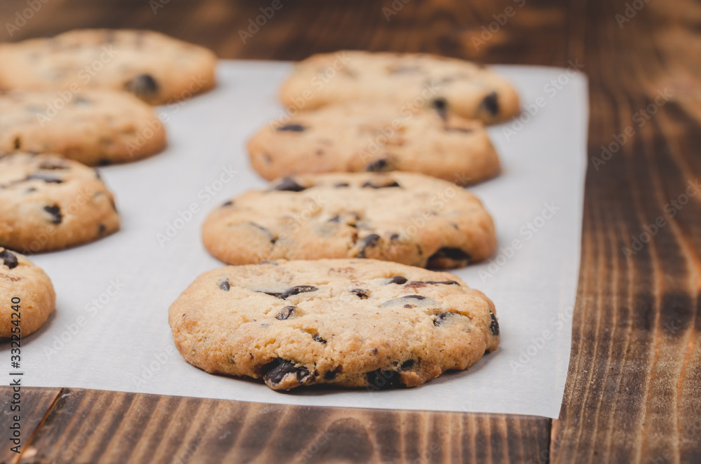 Cookies with chocolate filling on baking paper and wooden table/Cookies with chocolate filling on baking paper and wooden table. Fresh pastries. Cookies with chocolate filling on baking paper and wooden table/Cookies with chocolate filling on baking paper and wooden table. Fresh pastries.