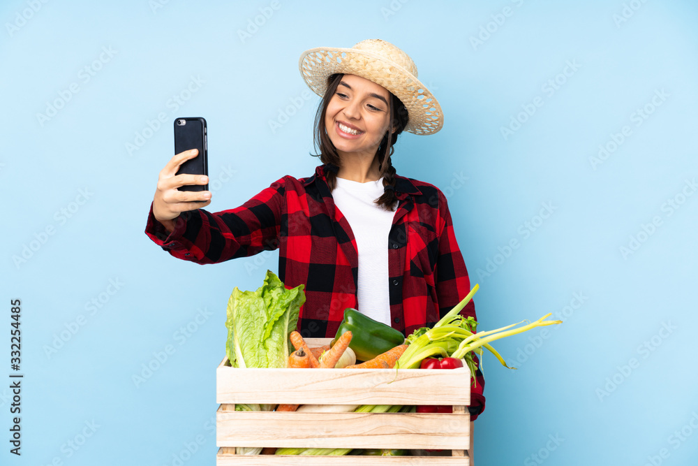 Young farmer Woman holding fresh vegetables in a wooden basket making a selfie