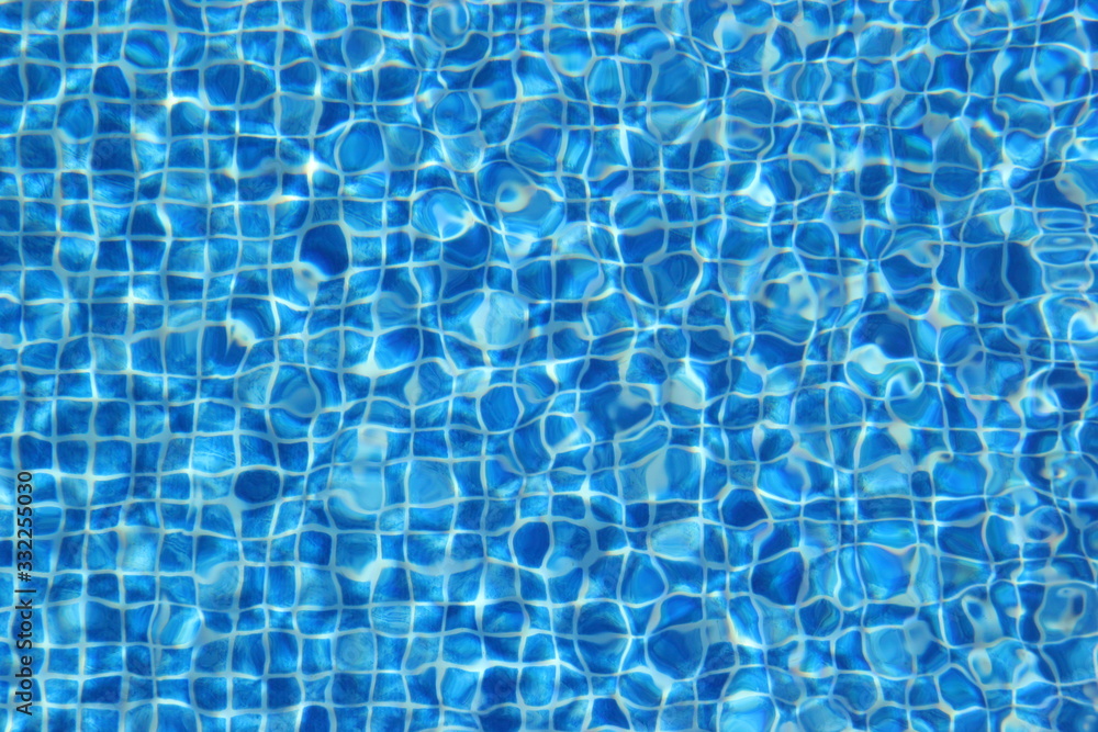 Top view of clear water in a blue tile pool background. Ripple effect