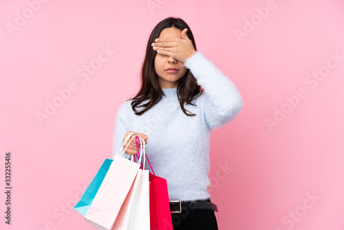 Young woman with shopping bag over isolated pink background covering eyes by hands. Do not want to see something