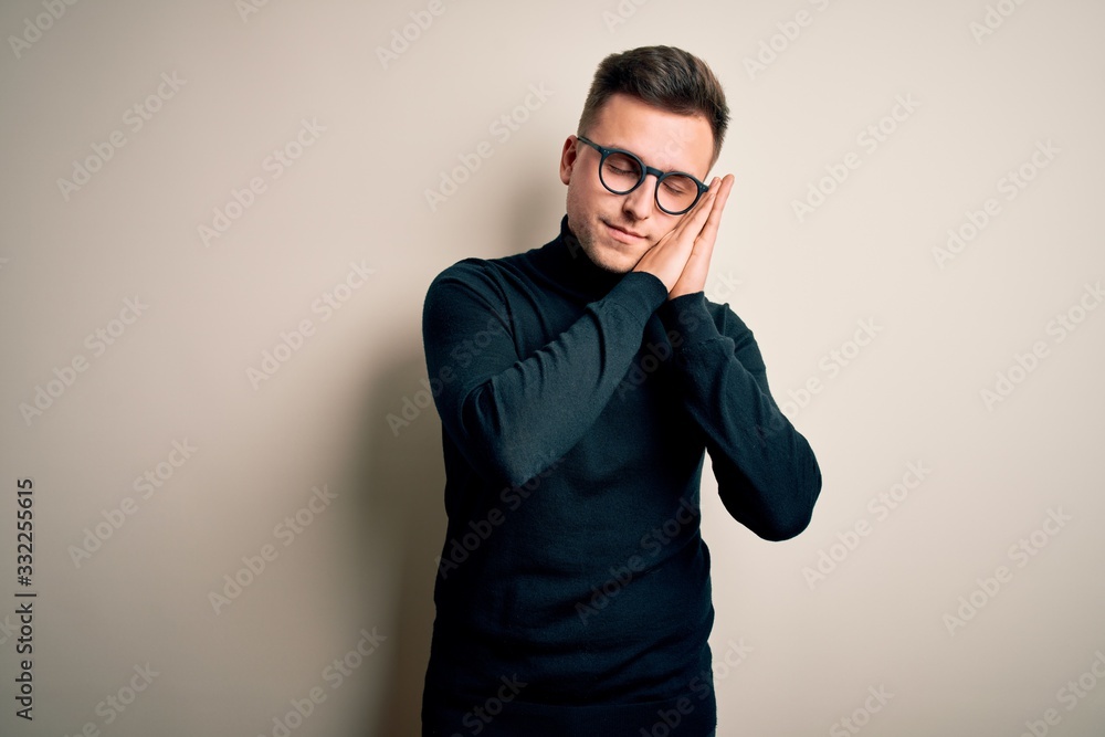 Young handsome caucasian man wearing glasses and casual sweater over isolated background sleeping tired dreaming and posing with hands together while smiling with closed eyes. Young handsome caucasian man wearing glasses and casual sweater over isolated background sleeping tired dreaming and posing with hands together while smiling with closed eyes.