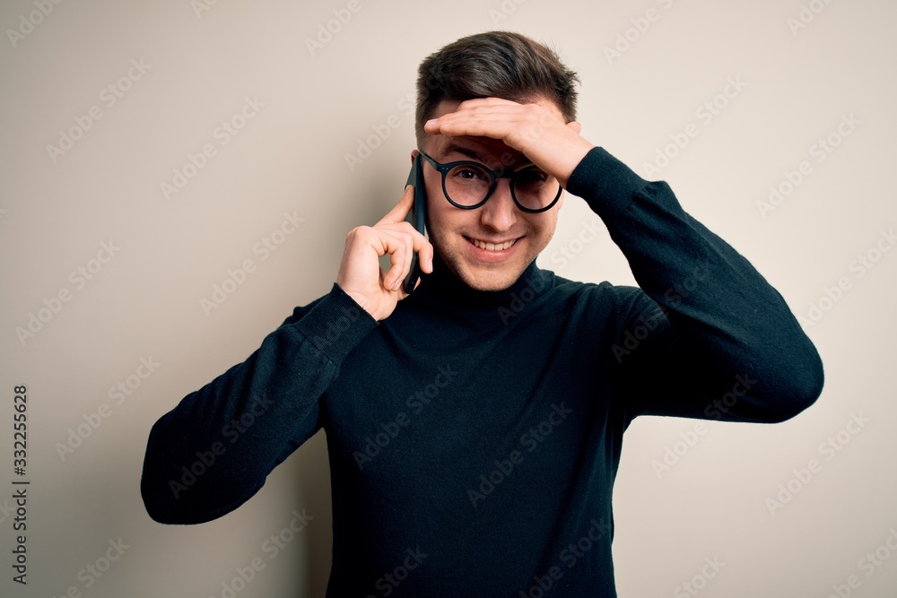 Young handsome caucasian man having a conversation talking on smartphone stressed with hand on head, shocked with shame and surprise face, angry and frustrated. Fear and upset for mistake. Young handsome caucasian man having a conversation talking on smartphone stressed with hand on head, shocked with shame and surprise face, angry and frustrated. Fear and upset for mistake.