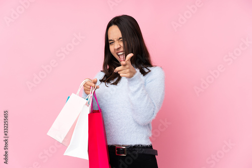 Young woman with shopping bag over isolated pink background pointing to the front and smiling