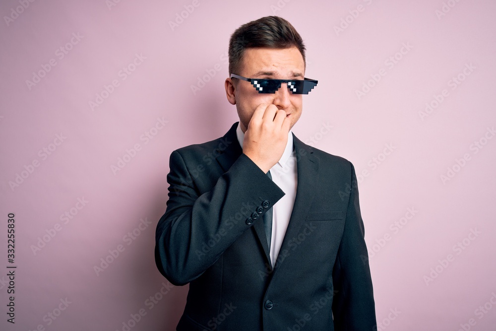 Young handsome caucasian business man wearing funny thug life glasses looking stressed and nervous with hands on mouth biting nails. Anxiety problem.