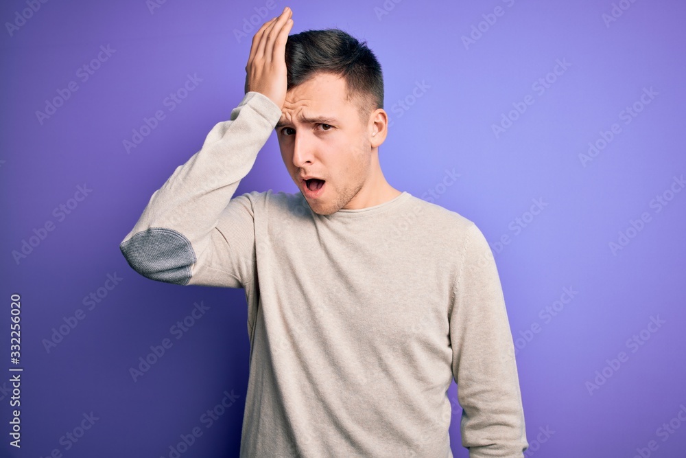 Young handsome caucasian man wearing casual sweater over purple isolated background surprised with hand on head for mistake, remember error. Forgot, bad memory concept. Young handsome caucasian man wearing casual sweater over purple isolated background surprised with hand on head for mistake, remember error. Forgot, bad memory concept.