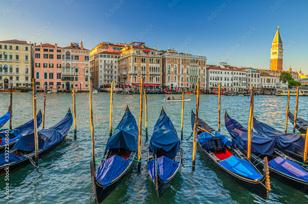 Gondolas moored on Grand Canal water in Venice. Baroque style colorful buildings along Grand Canal and Campanile di San Marco. Typical Venice cityscape, Veneto Region, Italy