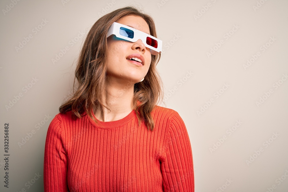 Young blonde girl wearing 3d cinema glasses over isolated background looking away to side with smile on face, natural expression. Laughing confident. Young blonde girl wearing 3d cinema glasses over isolated background looking away to side with smile on face, natural expression. Laughing confident.