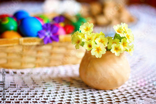 Foto Easter colorful eggs, flowers and greens, white tea-set with eggs inside the cups with butterflies thin porcelain, on a white rounded knitted tablecloth