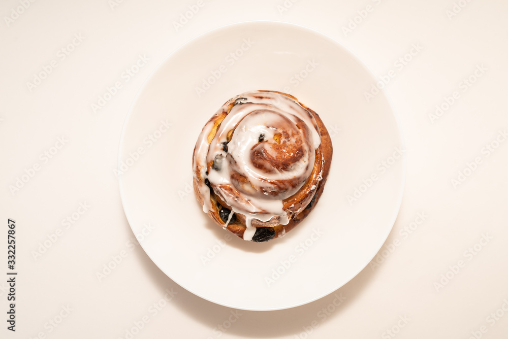bun with raisins in white plate on white background bun with raisins in white plate on white background