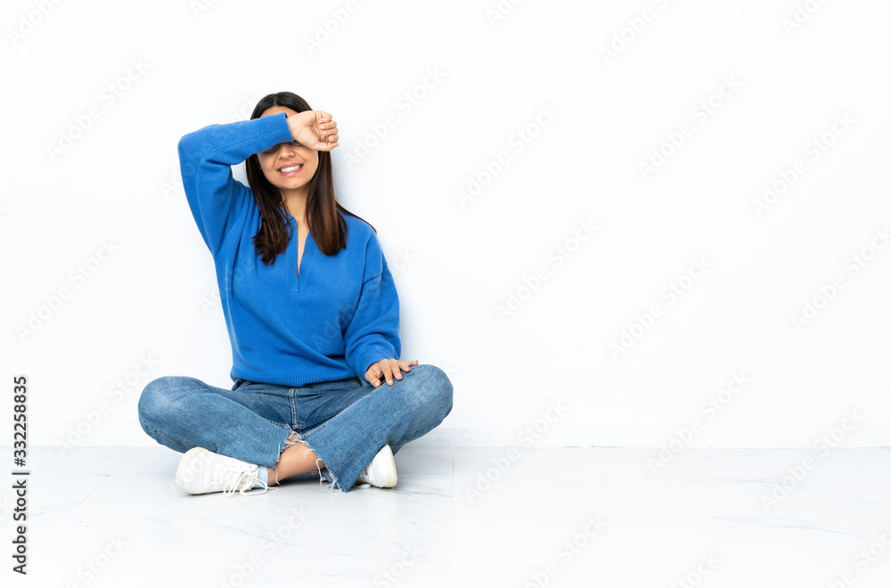 Young mixed race woman sitting on the floor isolated on white background covering eyes by hands Young mixed race woman sitting on the floor isolated on white background covering eyes by hands