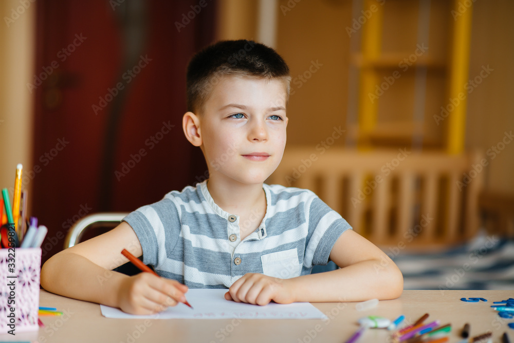 A school-age boy does homework at home. Training at school A school-age boy does homework at home. Training at school