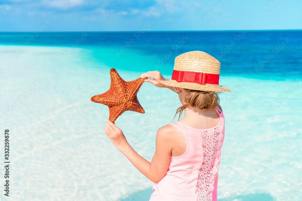 Adorable little girl with starfish on white empty beach Adorable little girl with starfish on white empty beach