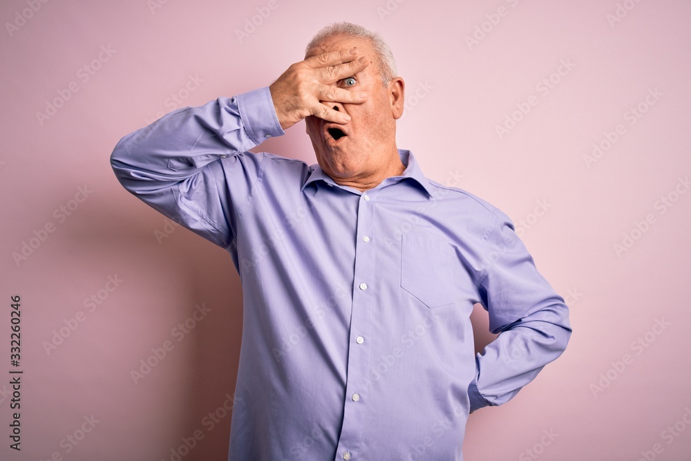 Middle age handsome hoary man wearing casual shirt standing over pink background peeking in shock covering face and eyes with hand, looking through fingers with embarrassed expression. Middle age handsome hoary man wearing casual shirt standing over pink background peeking in shock covering face and eyes with hand, looking through fingers with embarrassed expression.