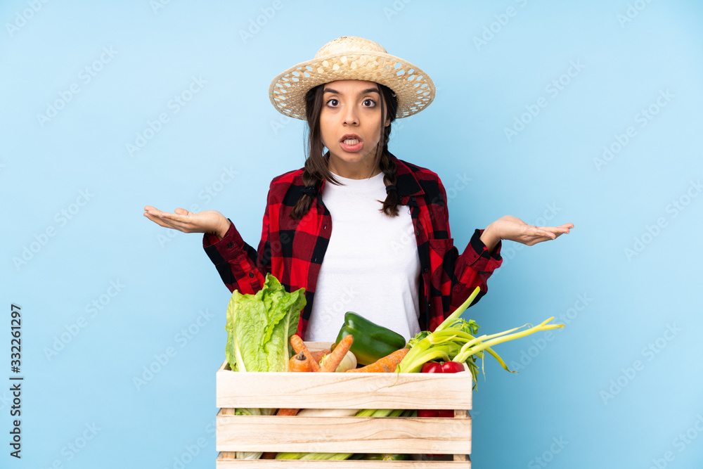 Young farmer Woman holding fresh vegetables in a wooden basket making doubts gesture