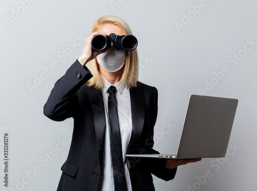 Businesswoman in black suit and face mask with binoculars and computer