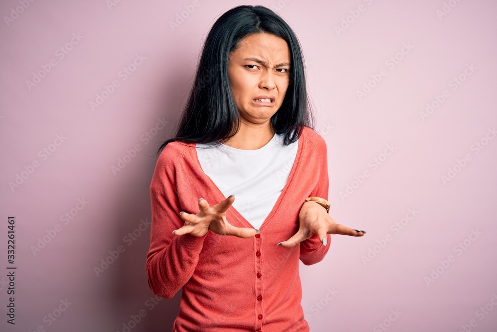 Young beautiful chinese woman wearing casual sweater over isolated pink background disgusted expression, displeased and fearful doing disgust face because aversion reaction. Young beautiful chinese woman wearing casual sweater over isolated pink background disgusted expression, displeased and fearful doing disgust face because aversion reaction.