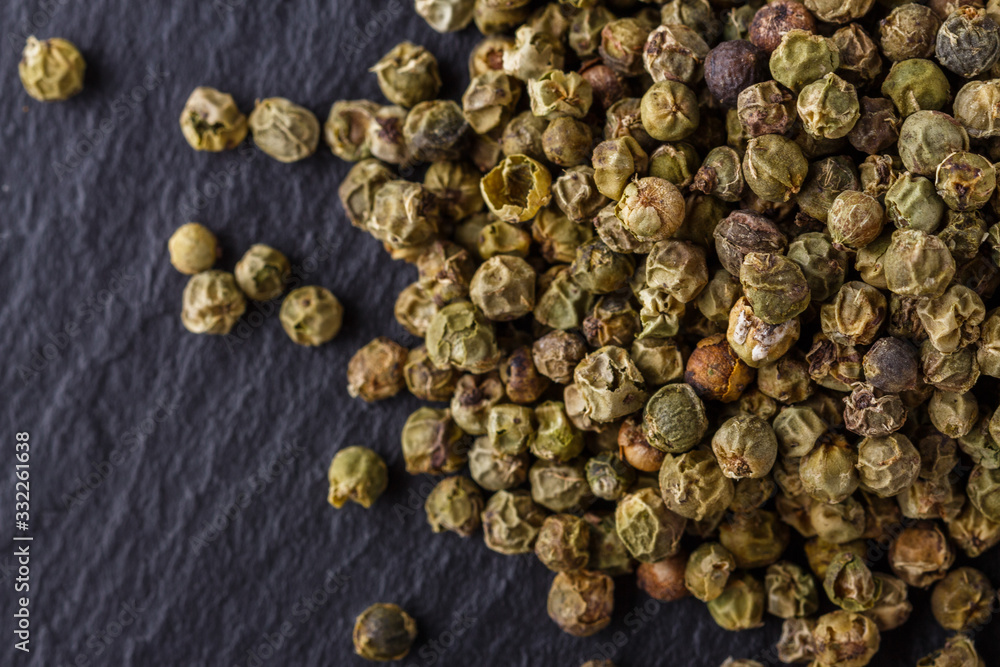 Obraz premium green peppercorns on dark slate stone background