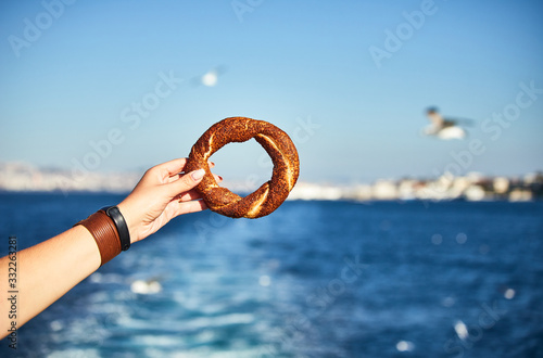 Simitci- a traditional Turkish round bagel with sesame seeds in hand on the background of the Sea of Marmara and the cityscape of Istanbul photo