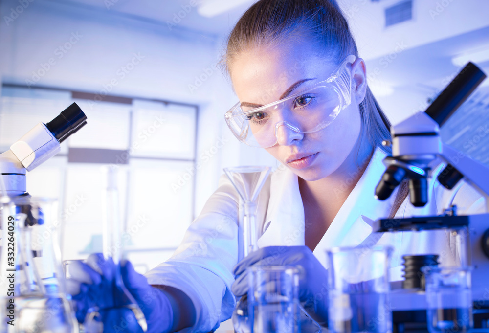 Laboratory interior. Science research concept. Young scientist during experiment and using microscope in modern laboratory. Laboratory interior. Science research concept. Young scientist during experiment and using microscope in modern laboratory.