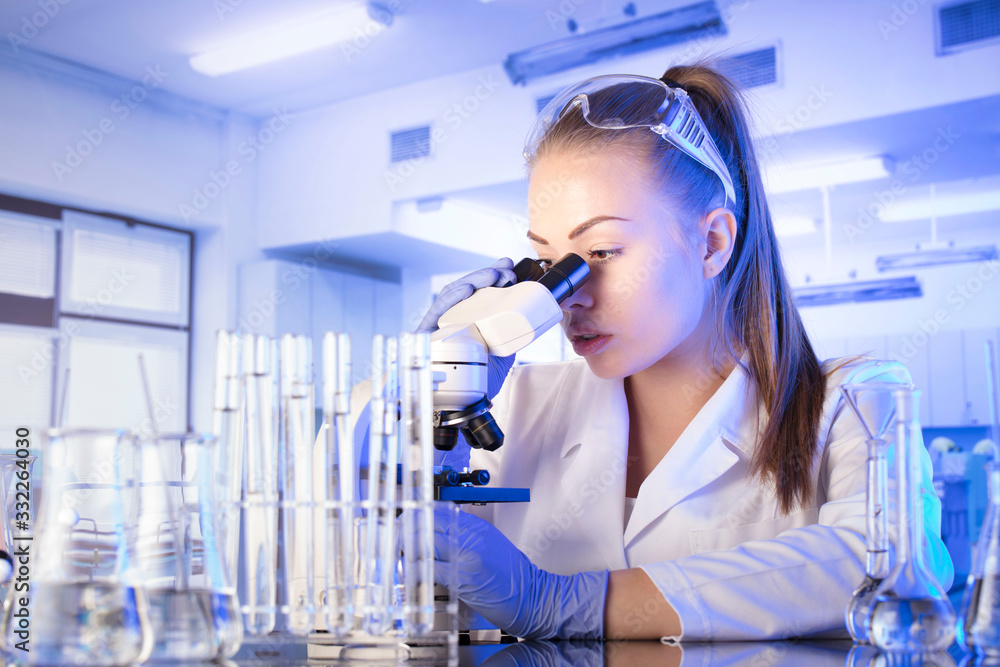 Laboratory interior. Science research concept. Young scientist during experiment and using microscope in modern laboratory. Laboratory interior. Science research concept. Young scientist during experiment and using microscope in modern laboratory.