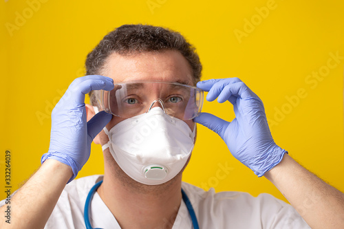 Medical worker wearing glasses as personal protective equipment on yellow background photo